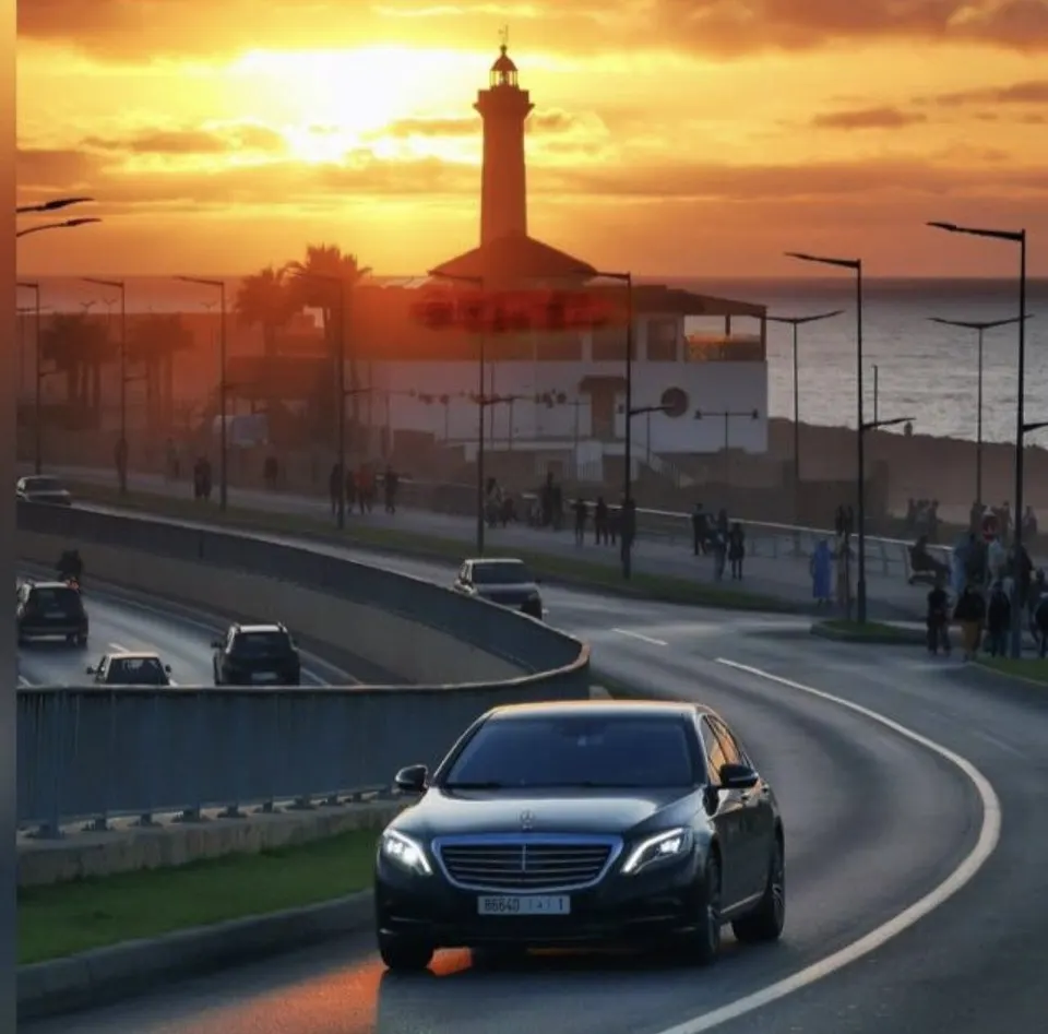 Mercedes Classe S noire sur la corniche au coucher du soleil, phare en arrière-plan